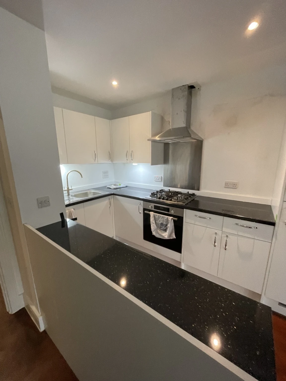 Completed kitchen with white cabinetry and dark worktops
