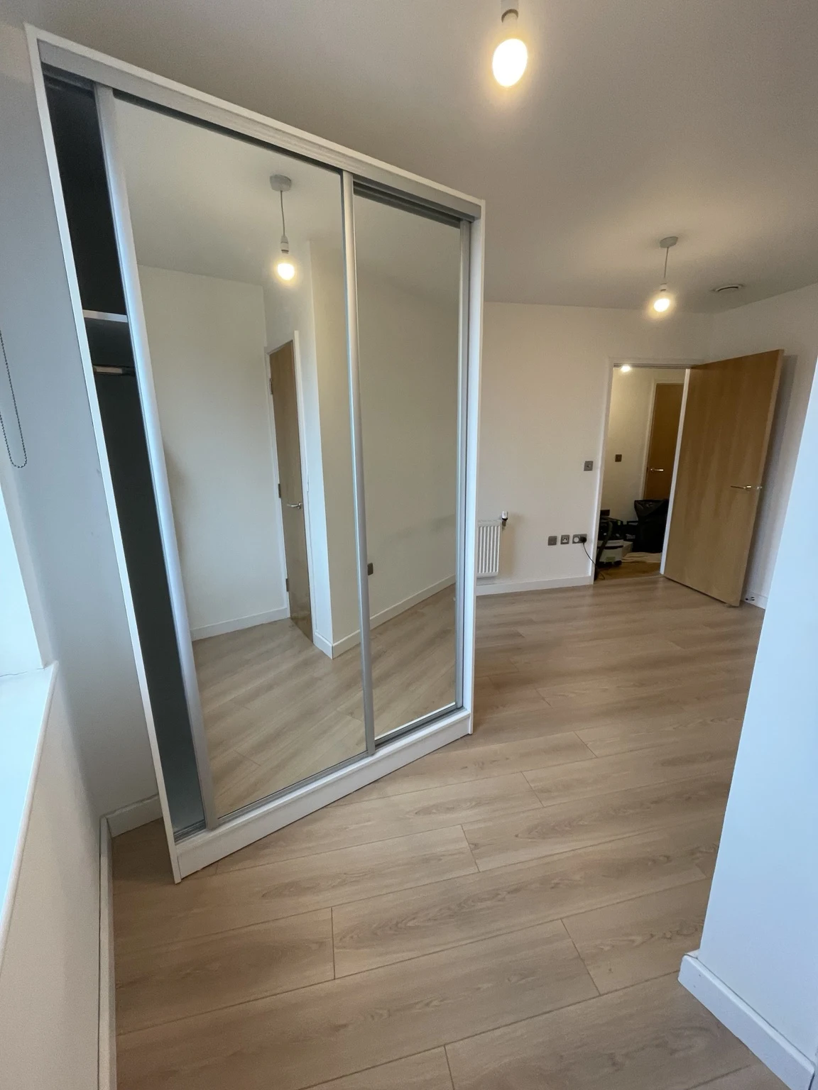 Sliding mirrored fitted wardrobe and timber flooring